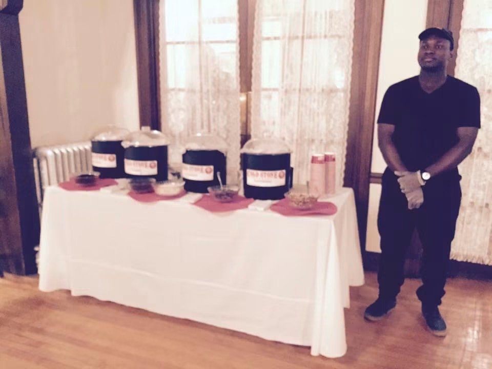 An indoor Cold Stone sundae-bar table set with branded catering tubs before an event