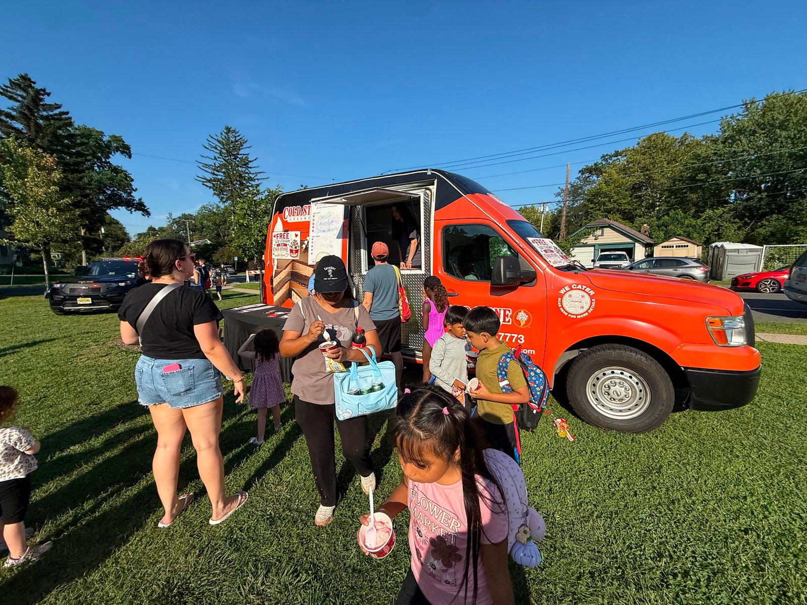 Families with children being served at the Cold Stone truck parked on a residential street