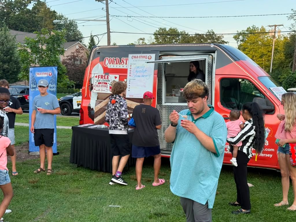 A young guest holding a cup of ice cream at an outdoor event with the Cold Stone truck behind